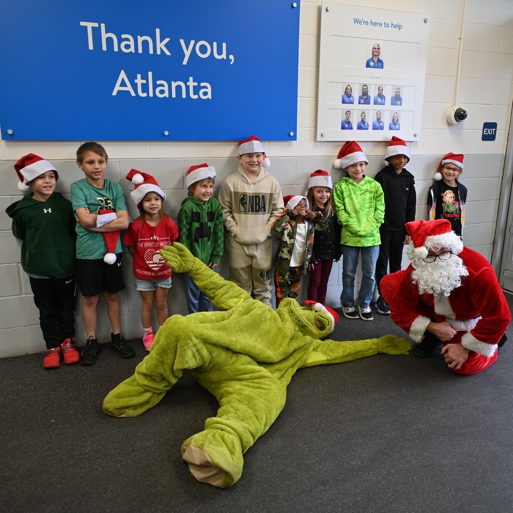 Ten students chosen for Shop with a Cop pose with Santa and the Grinch outside the Atlanta TX Walmart