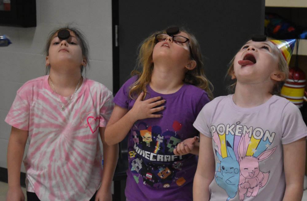 3rd grade girls playing a game trying to get oreos from their foreheads to their mouths without their hands