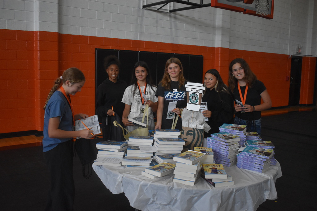 a group of students smiling as they check out the fantasy book options
