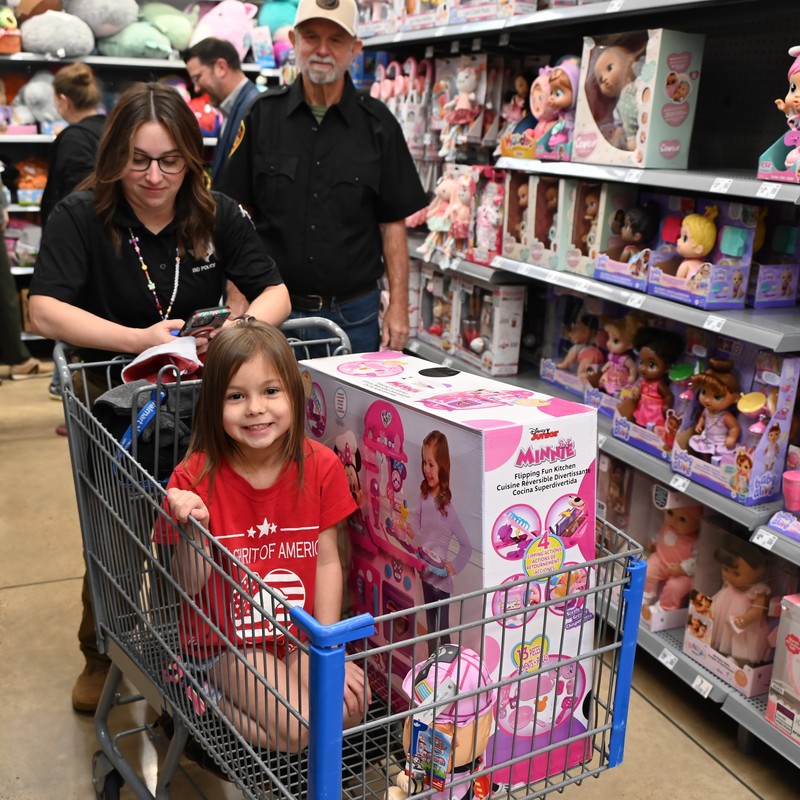 student riding in a grocery cart during Shop with a Cop Adventure
