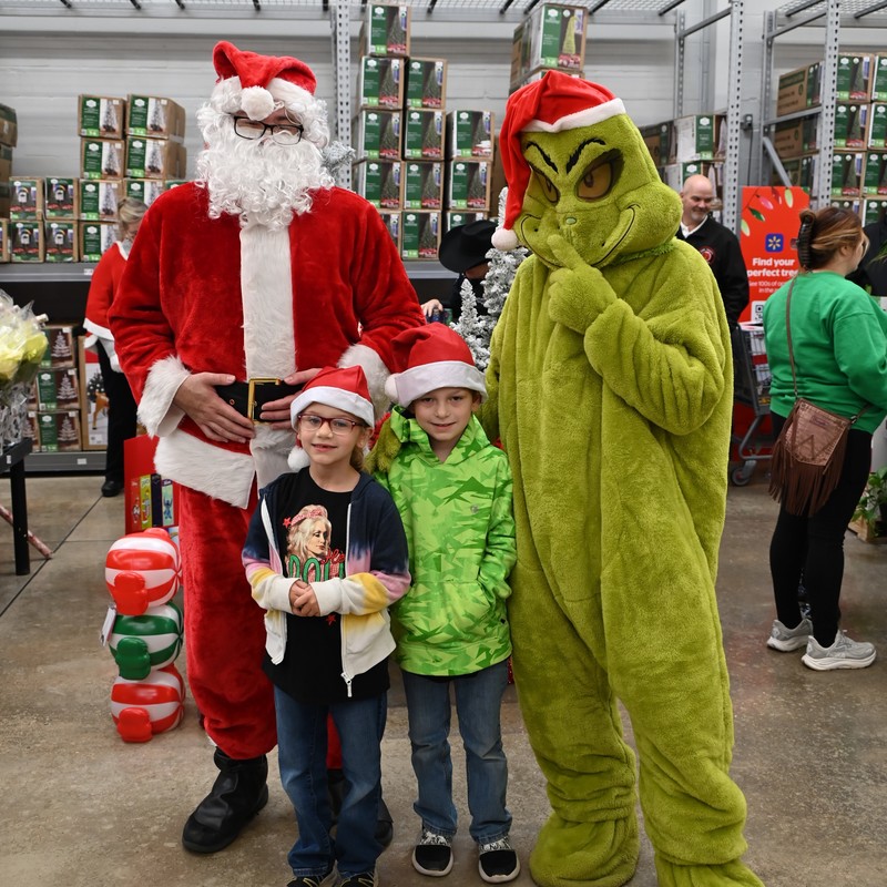Brother and sister pose with Santa and the Grinch during Shop with a Cop