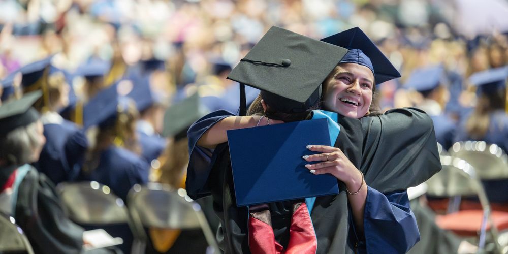 QHS graduate hugs teacher at graduation.