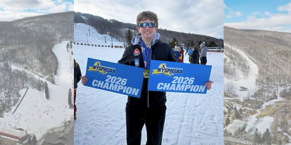 Wesley Fuller stands at bottom of ski mountain with 2026 champion signs.
