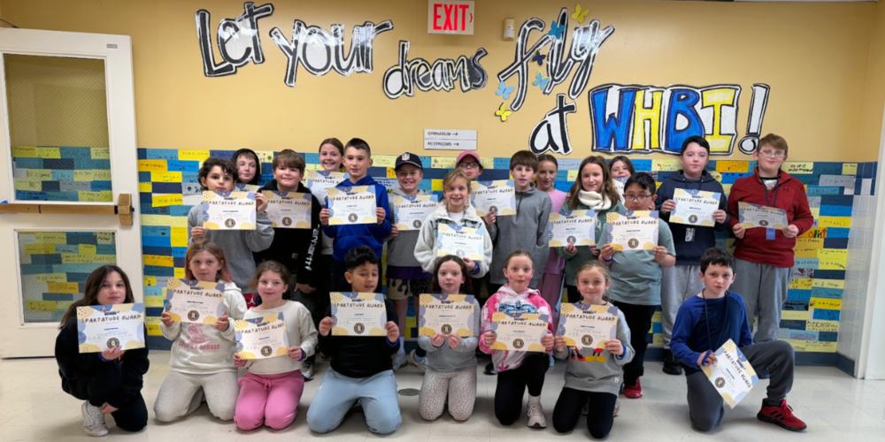 Students stand in WHBI hallway with certificates.