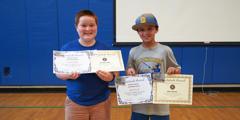 Two students stand with certificates.