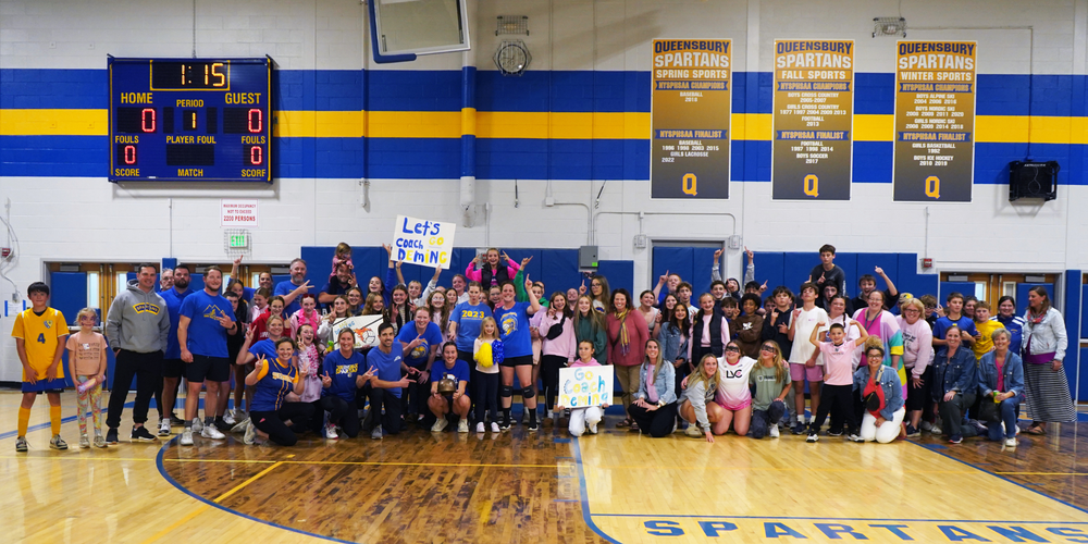 Group of students and staff celebrate volleyball victory.