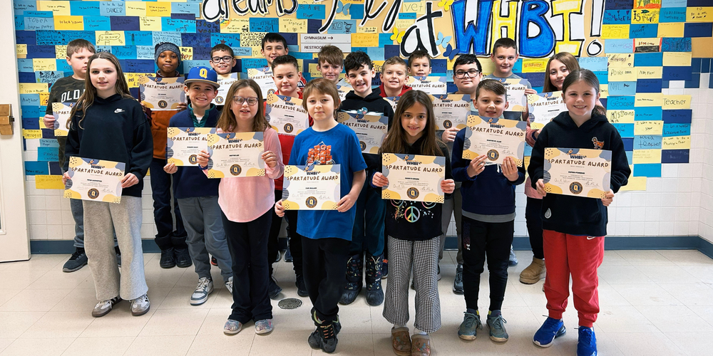 Group of students stand in school hallway holding certificates.