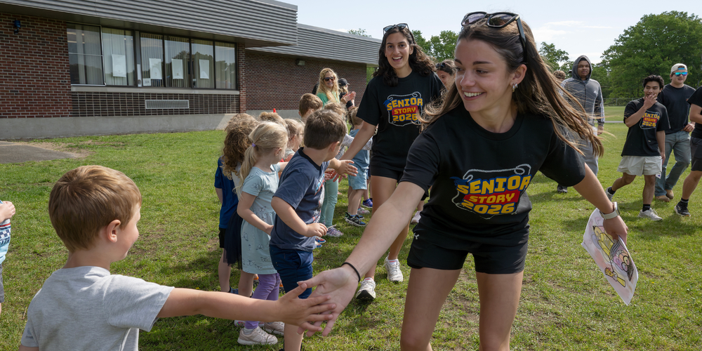 Student high fives younger student.
