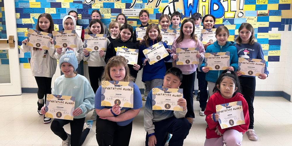 WHBI students stand in hallway with Spartatude certificate.