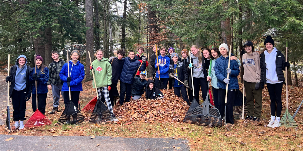 QMS students hold rakes and volunteer at Double H Ranch.