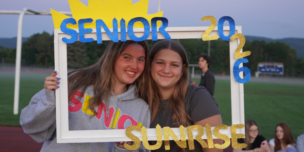 Two students stand with Senior Sunrise frame.