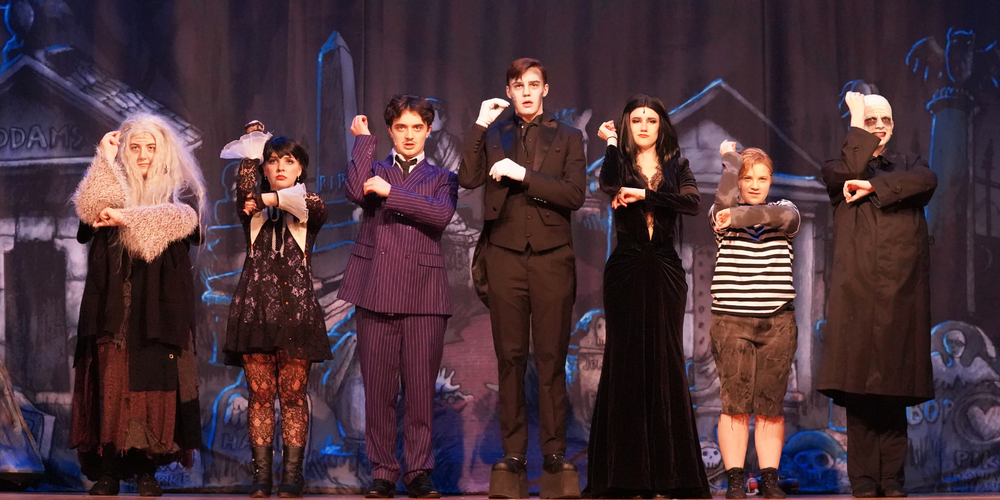 Cast of 'The Addams Family' performs a song on stage.