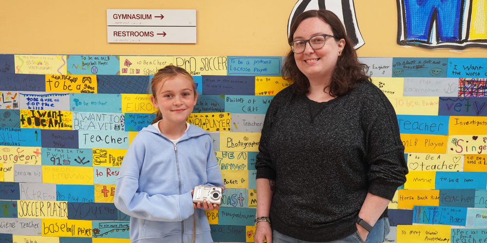 Charlotte Derue, left, receives a camera from Jess Keller.