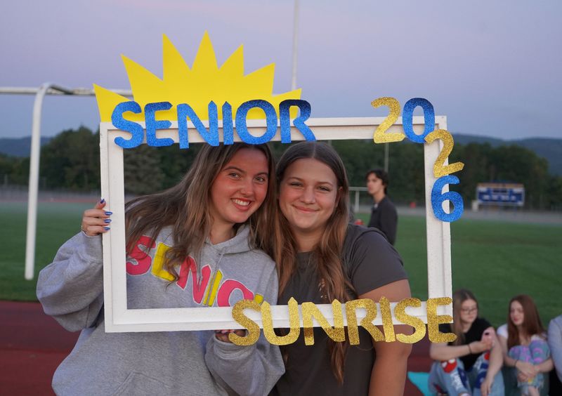 Two high school seniors pose with Senior Sunrise frame.