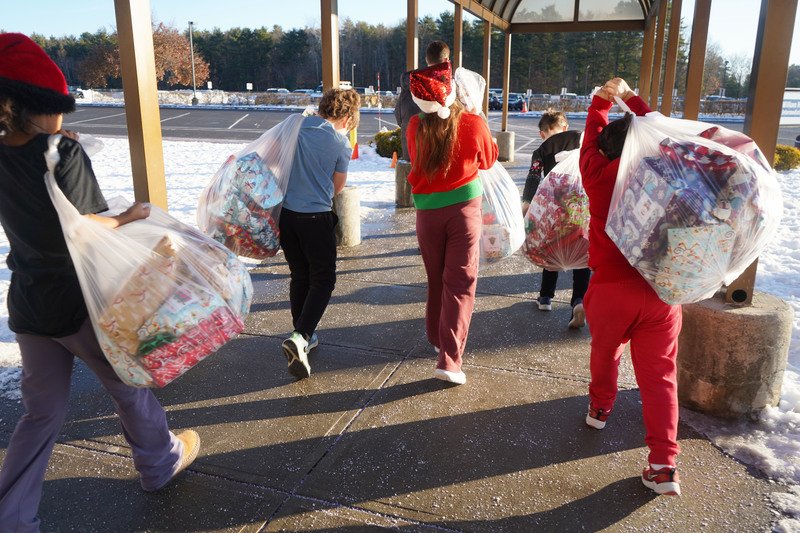 Students carry bags of presents to be donated.