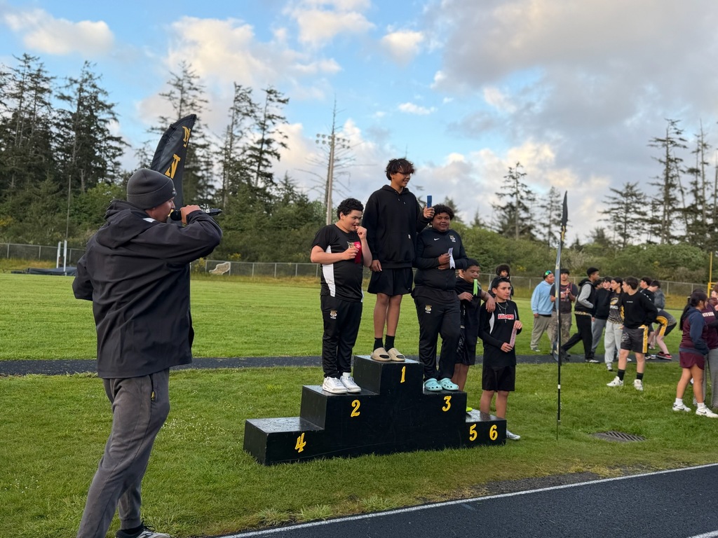 Boys Track and field standing podium with track athletes standing on it. 
