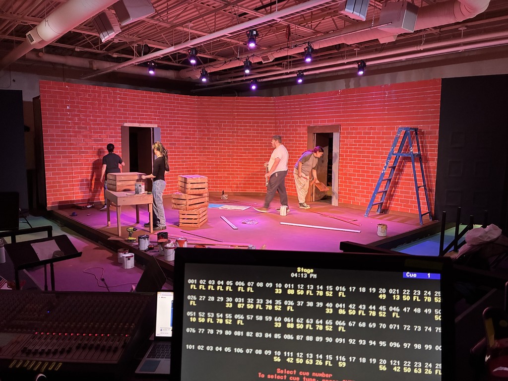 Stage with 4 students building walls and background.