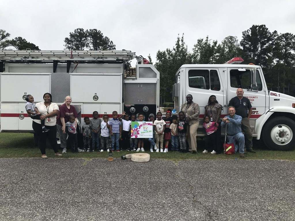 group of students smiling for group photo infront of a fire truck