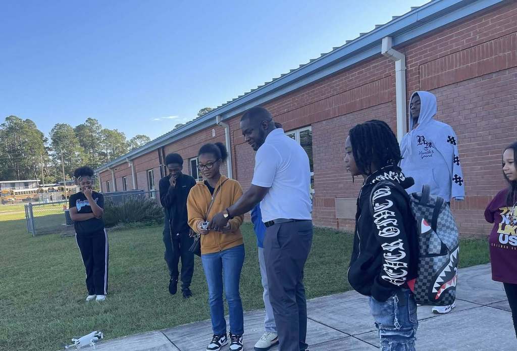 Group of students and teachers huddled in a group reviewing the school grounds