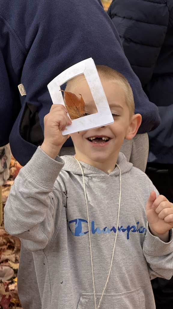 A student smiles as he looks at a leaf through a viewing window.