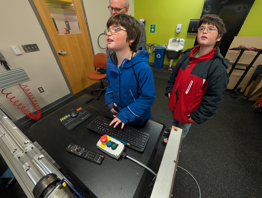 Two students and an instructor use a keyboard to program a robot with coding.