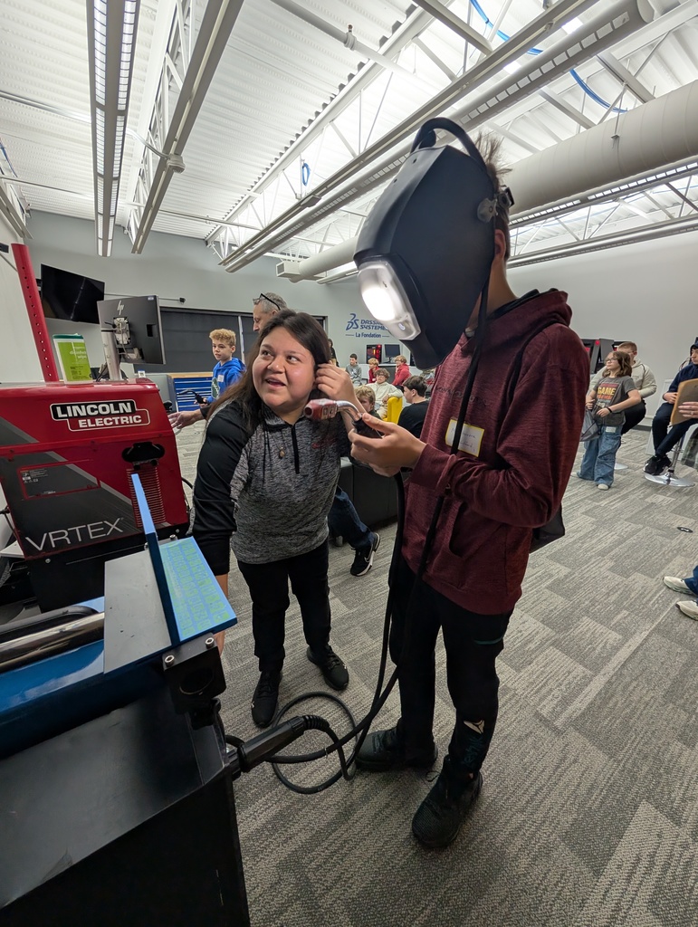 A student using a welding simulator with the help of an instructor.
