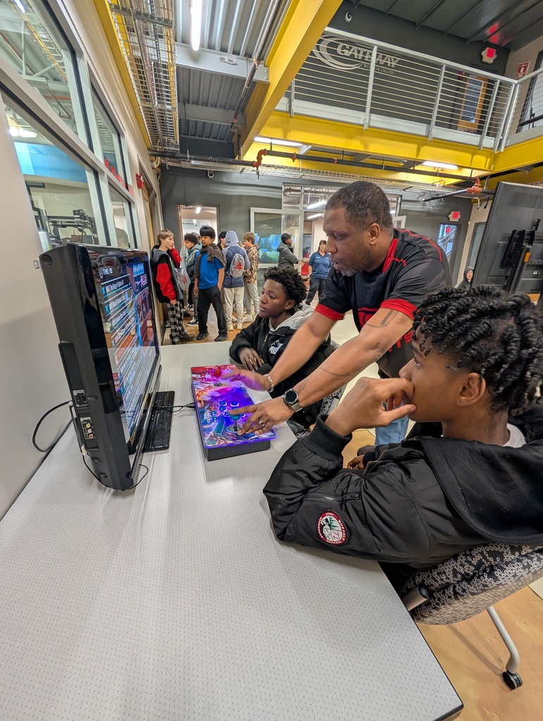 An esports coach shows two students how to play a game.