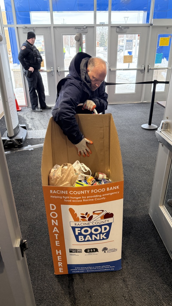A gentleman from the Racine County Food Bank loads a food box onto a moving dolly.