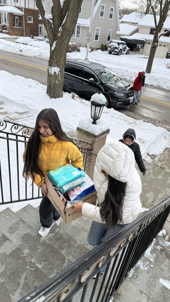 Two female Mitchell students delivering a large box of supplies to the Women's Resource Center.