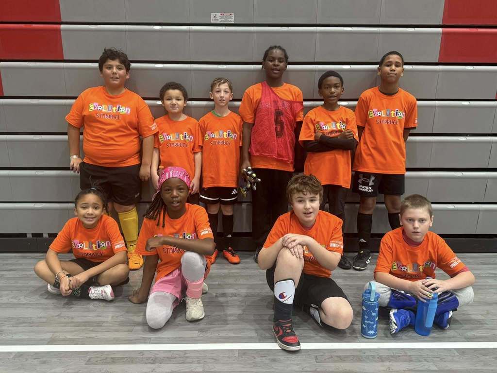 Ten students wearing their Evolution soccer league shirts, standing in front of bleachers.