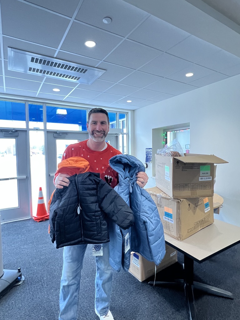 Marcus Hanel posing with four big boxes filled with coats that Koos For Kids donated to Olympia Brown School.