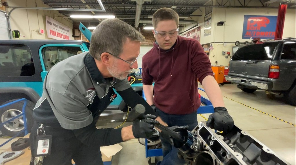 A student learning how to repair a piston in an engine.