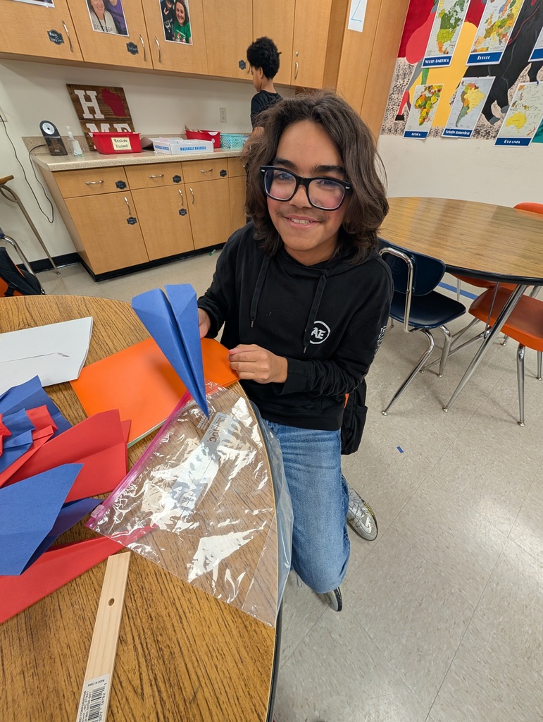 A male student folds paper airplanes for his marketplace.