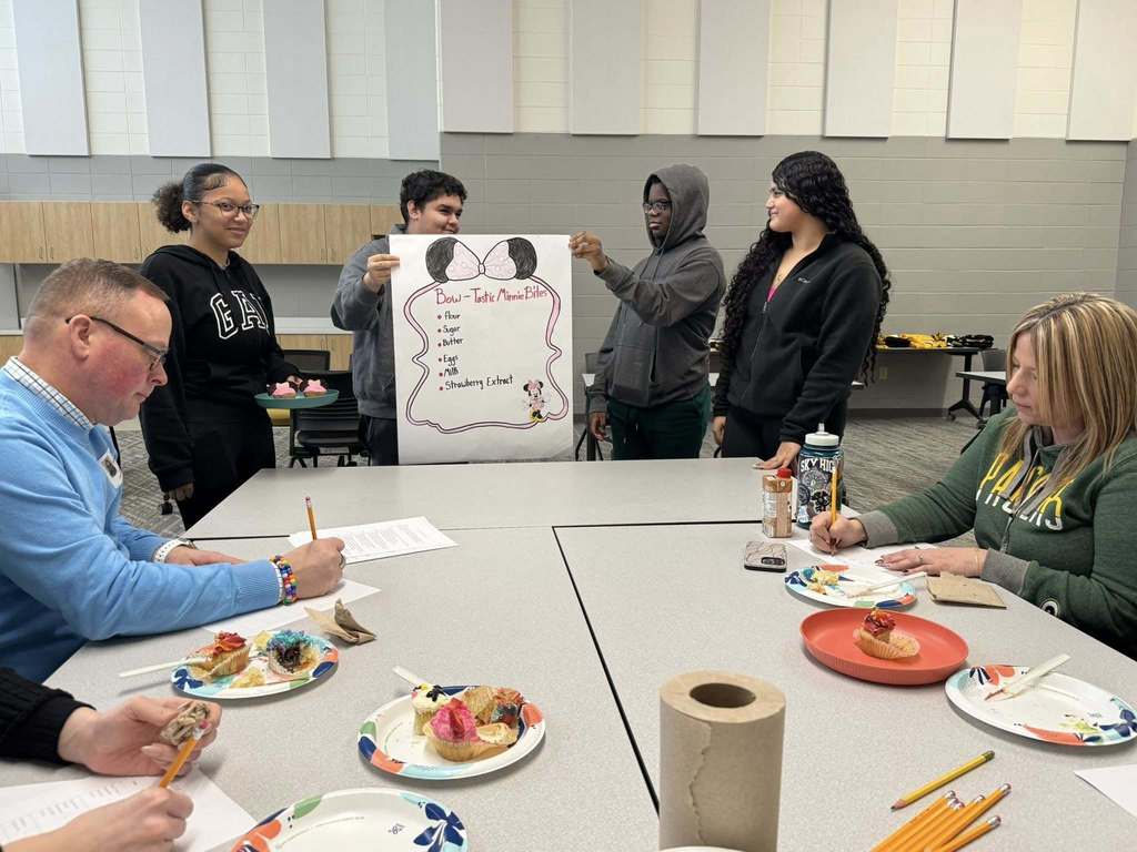 Students presenting their cupcake designs to the judging panel.