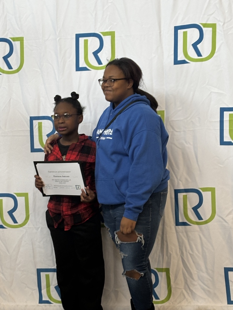 A student holding their award and posing with a parent or teacher at this year's MLK Art and Essay awards show.