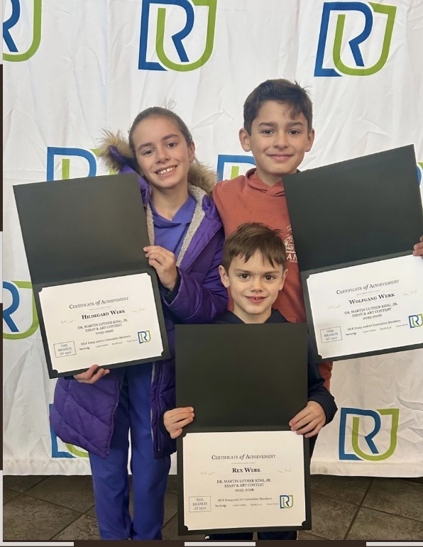 Three students holding their awards at this year's MLK Art and Essay awards show.