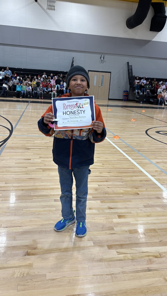 An elementary boy stands with his student of the month certificate celebrating his nomination for student of the month for exemplifying honesty in all they say and do!