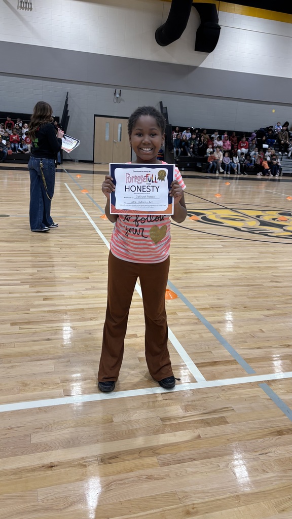 A 3rd grade girl stands with her student of the month certificate celebrating her nomination for student of the month for exemplifying honesty in all they say and do!