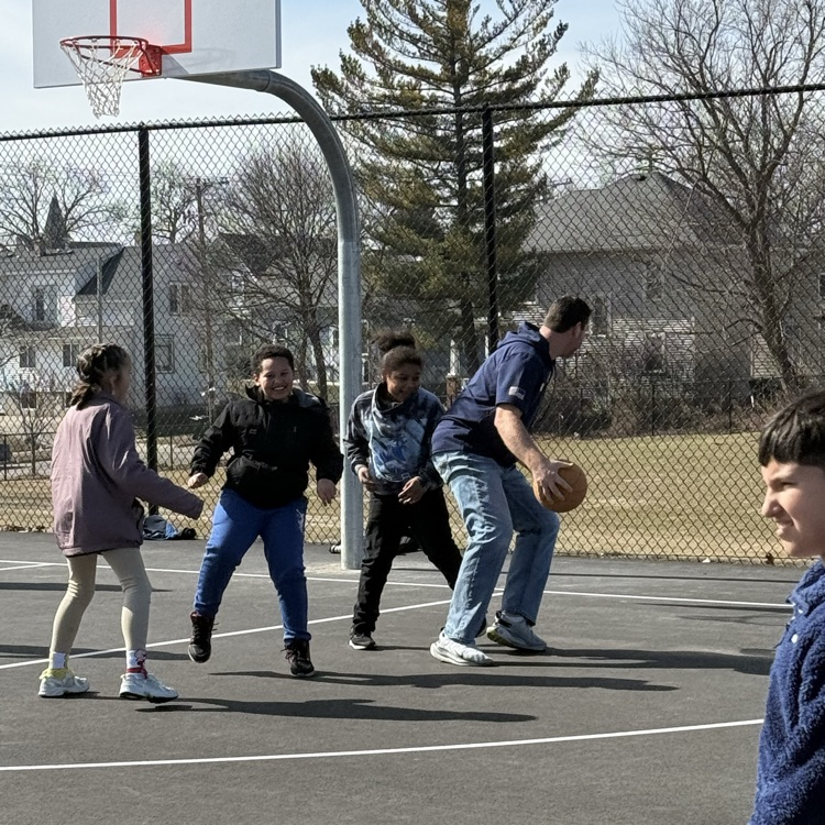 Marcus playing basketball with several students