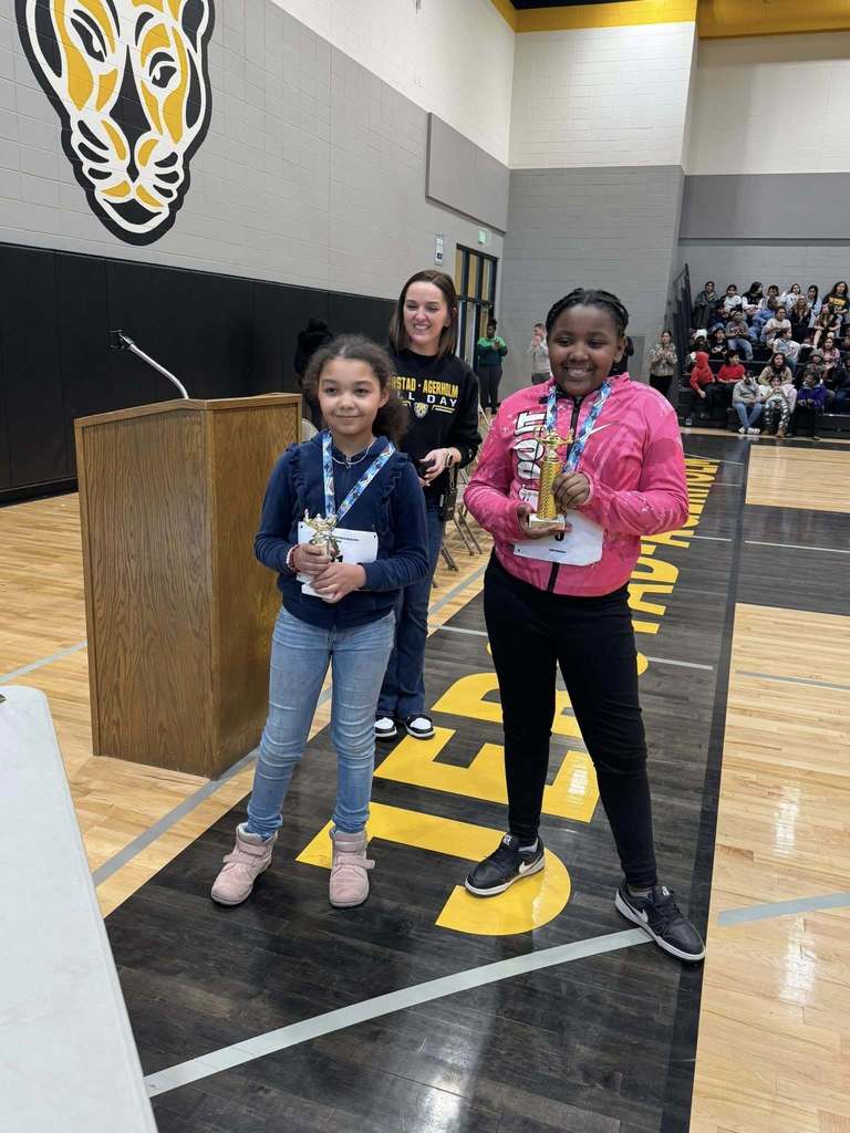 The first and second place winners stand with their trophies with the K-3 principal standing behind them.