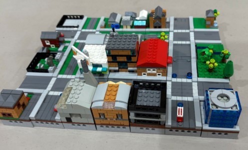 A small city made of LEGO. It is a 6 x 7 grid made of interlocking building and street sections.