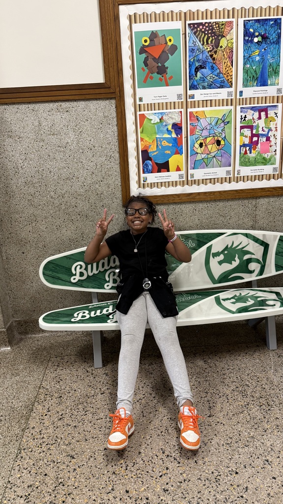 A fourth grader sits on the bench with legs outstretched in front of her and two peace signs.