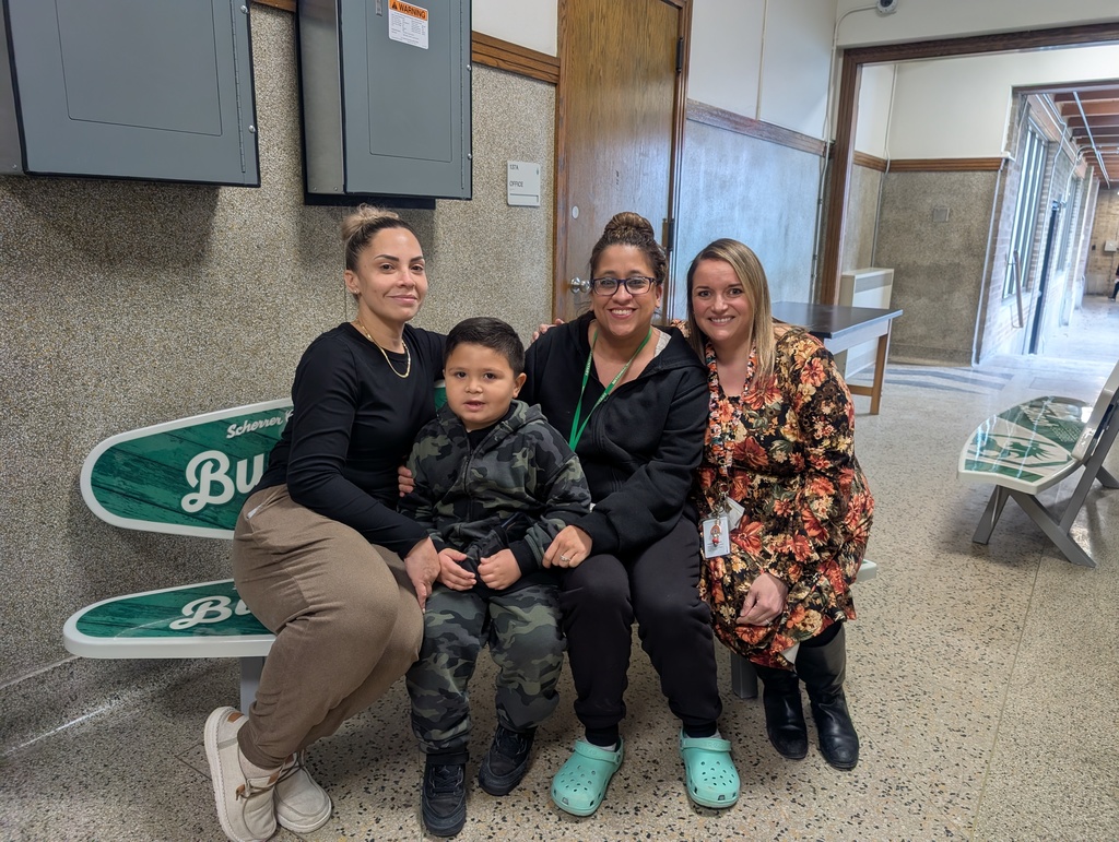 Four people sit on the Buddy Bench. From left to right, a woman, a boy, and two more women.