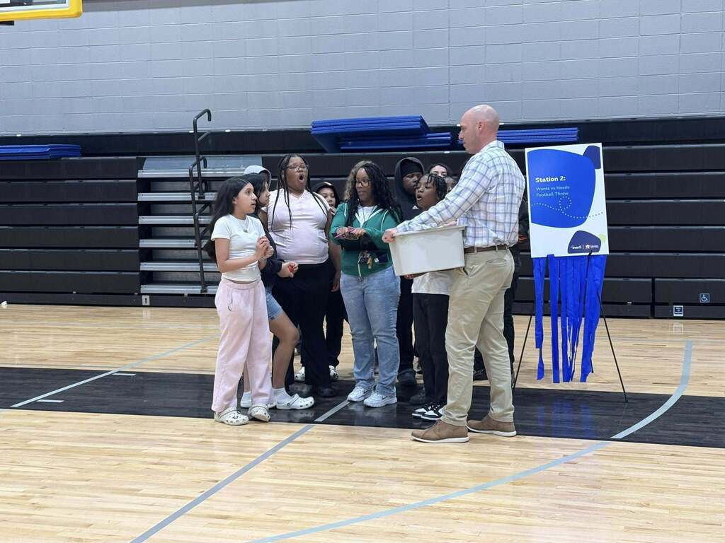 Students listen to directions from a staff member for the game they are going to play as part of the Everfi celebration.