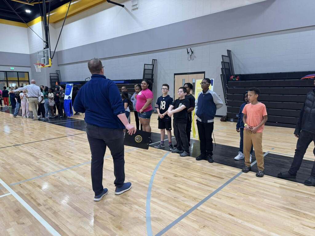 Students listen to directions from a staff member for the game they are going to play as part of the Everfi celebration.