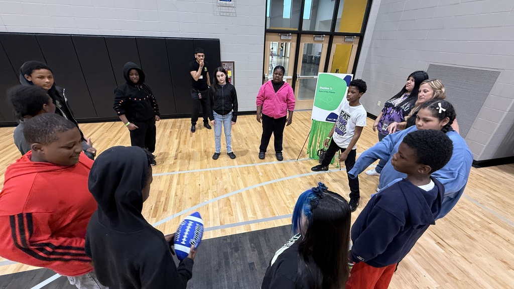 A group of student standing in a circle playing hot potato with a football.