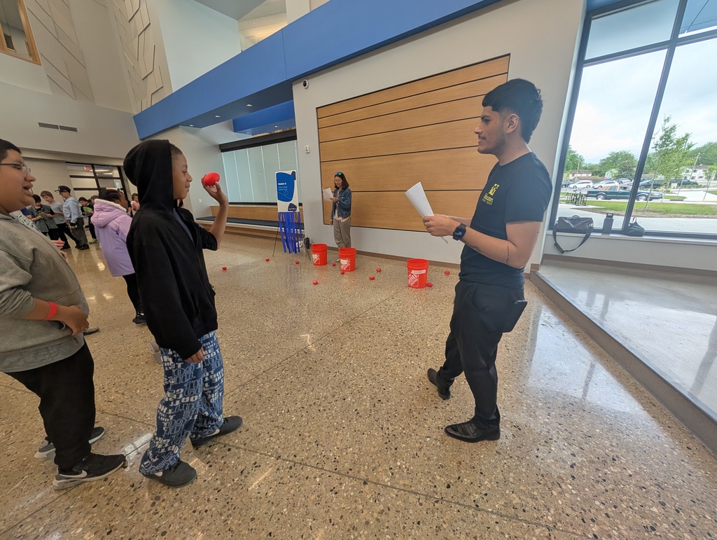 A volunteer watching a student play a bucket toss game.
