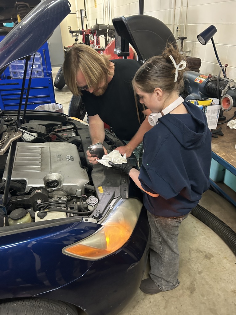 A Mitchell student checks the oil level on a dip stick.