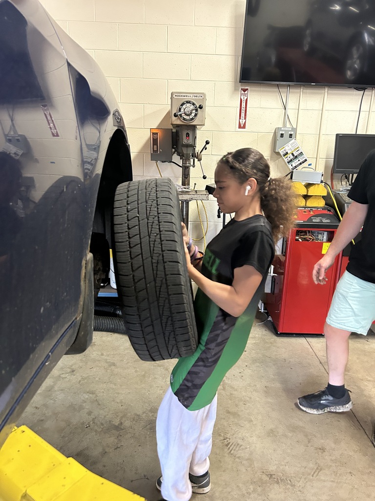 A Mitchell student removes a car tire.