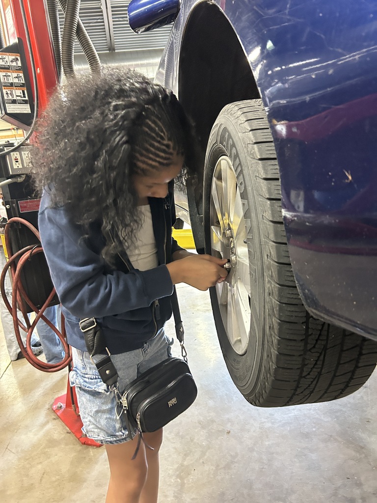 A Mitchell student places lug nuts back onto a car.